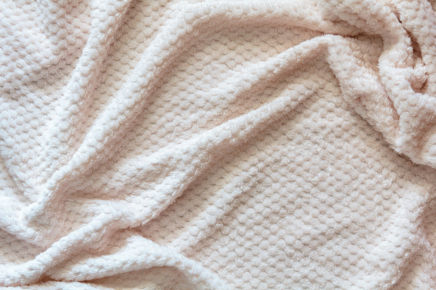 A wool blanket with gentle wrinkles, showcasing its soft texture and cozy appearance, ideal for a warm and inviting setting.